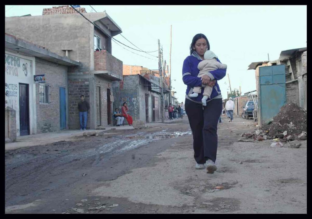 A woman walks with her baby through a Buenos Aires' slum